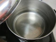 a metal pan sitting on top of a stove next to an oven burner with a lid