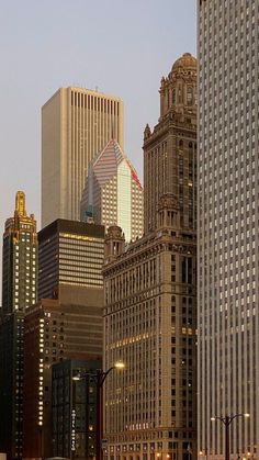 there are many tall buildings in the city at sunset or dawn, as seen from across the street