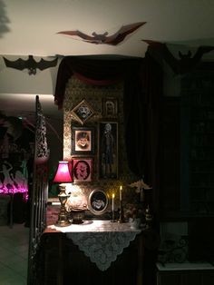 a table with candles and pictures on it in a room filled with bats hanging from the ceiling