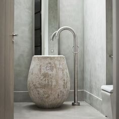 a white toilet sitting next to a tall mirror in a bathroom under a light fixture