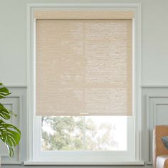 a living room with white walls and a window covered in beige roman blind shades that are hung on the windowsill