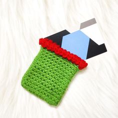 a crocheted cell phone case with a red flower on the side and a green cover