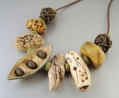 a necklace made out of different types of beads on a white surface with brown cord