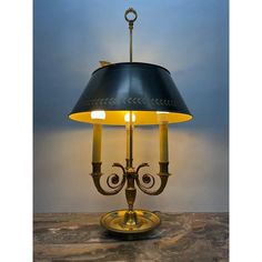 a table lamp with a black shade on it and a gold plated metal base