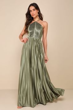 a woman in a long green dress with halt neck and pleaed skirt, posing for the