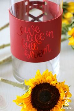 a sunflower sitting next to a wine glass with the words live in love soon written on it