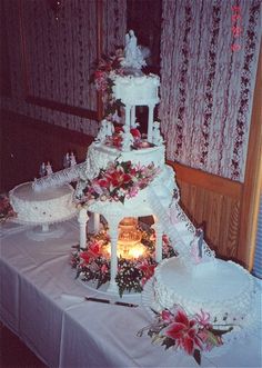 three tiered wedding cake sitting on top of a table next to two lit candles