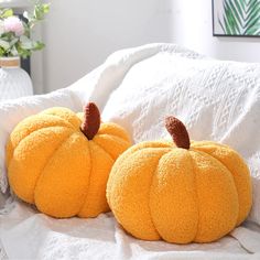 two yellow pumpkins sitting on top of a bed