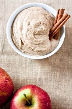 two apples and cinnamon sticks next to an apple dip