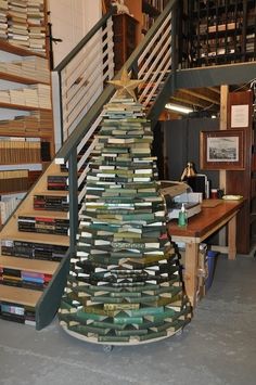 there is a christmas tree made out of books on the floor next to a staircase