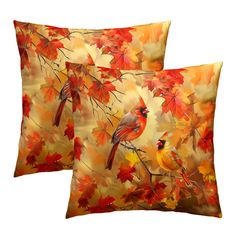 two red and yellow pillows with birds sitting on the tree branches in front of them