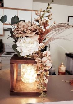 a vase filled with flowers sitting on top of a wooden table next to a light