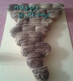 a birthday cake with the shape of a tornado on it's side that says happy birthday