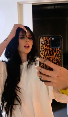 a woman taking a selfie in front of a mirror while holding a cell phone