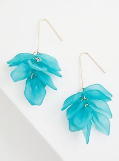 a pair of blue flower earrings sitting on top of a white surface