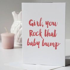 a card with the words girl, you rock that baby bump on it next to a candle