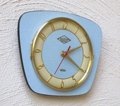 a clock that is on the side of a wall with blue and gold trim around it