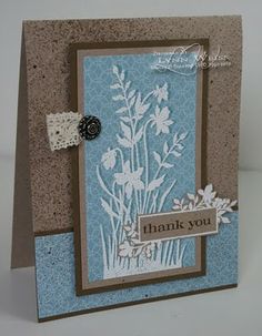 a handmade thank card with white flowers on blue and brown paper, which says thank you