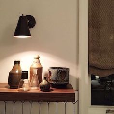 a table topped with vases and lamps next to a wall mounted clock on a wall