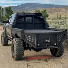 the truck is parked on the side of the road in front of some bushes and mountains