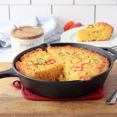 a skillet with some food in it on top of a wooden table next to plates and utensils