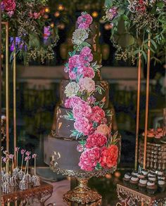 there is a cake with flowers on it and cupcakes in the foreground