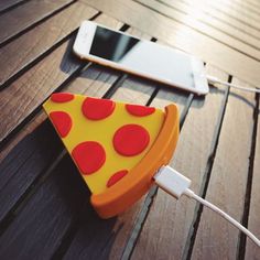 a slice of pizza sitting on top of a wooden table next to a cell phone