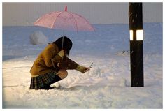 a woman kneeling in the snow with an umbrella