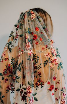 the back of a woman's blouse with flowers on it and sheer fabric over her shoulders