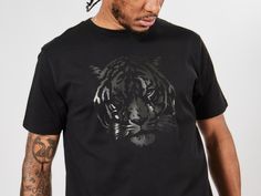 Embrace the spirit of the jungle with our captivating Tiger T-Shirt, embodying strength and wild allure. Let the untamed energy of the tiger fuel your confidence and make a fearless statement in any setting. Featuring a striking tiger face design, this shirt exudes confidence and power. Channel the energy of the wildcat and stand out from the crowd with this captivating and bold graphic. Crafted with the finest materials, our Tiger Shirt offers unparalleled comfort and durability. The soft cotto Black Tiger Print Crew Neck Top, Black Crew Neck Top With Tiger Print, Eyes Animal, Tigers Shirt, Go Tigers, Tiger Eyes, Tiger King, Tiger Shirt, King Shirt