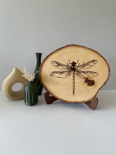 a dragonfly sitting on top of a piece of wood next to two vases