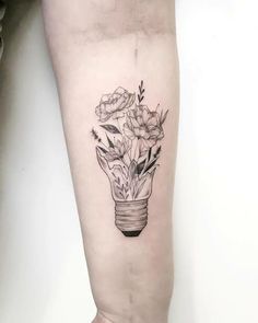 a woman's leg with flowers in a light bulb tattoo