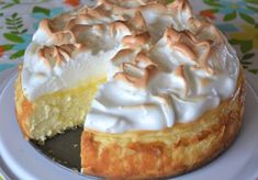 a lemon meringue pie on a plate with one slice cut out and ready to be eaten