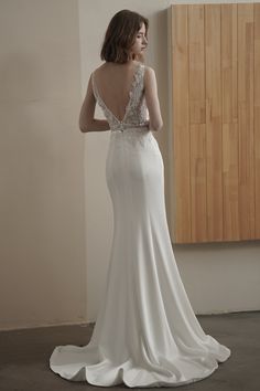 a woman in a white wedding dress looking out the window with her back to the camera