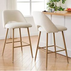 two white bar stools sitting in front of a window