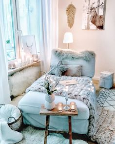 a living room filled with lots of furniture next to a large window covered in white curtains