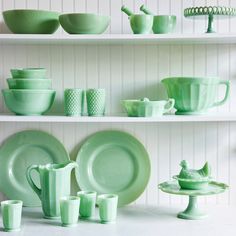 the shelves are filled with green dishes and cups