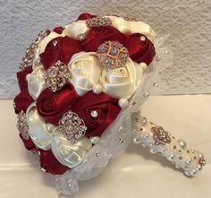 a bridal bouquet with red and white roses, pearls and diaper on it