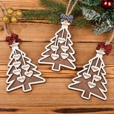 three wooden christmas tree ornaments on a table