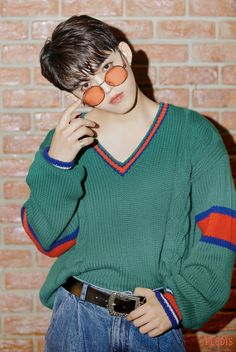 a young man wearing an orange pair of glasses on his face while standing in front of a brick wall