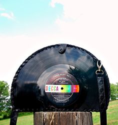 a record sitting on top of a wooden post in the middle of a green field