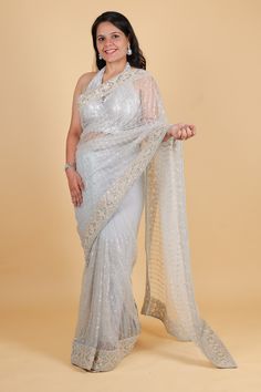 Indulge in luxury with our net designer saree in a stunning blue hue. Adorned with delicate thread embroidery and sparkling sequins, this saree exudes sophistication and elegance. Perfect for any occasion, its lightweight net fabric drapes beautifully for an effortlessly glamorous look. Elevate your style with this exclusive piece. Net designer saree with thread embroidery and sequin work - blue color Saree comes with a blouse piece. Fall and pico done. Fully stitched blouse shown in pictures is optional and can be purchased seperately from our blouses and croptops section. For saree video please connect with us on whatsapp @469-937-0606 Ready to be shipped in USA from San Diego, California. All pictures are original pictures. Colors may slightly vary due to pic resolution. Silver Georgette Pre-draped Saree For Wedding, Party Wear Organza Saree With Cutdana, Sequin Organza Saree For Wedding, Silver Semi-stitched Pre-draped Saree For Designer Wear, Silver Pre-draped Saree With Mirror Work For Diwali, Traditional Organza Saree With Sequins, Festive Organza Saree With Sequins, Organza Pre-draped Saree With Sequins, Festive Sequined Organza Saree