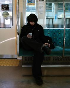 a man sitting on a subway looking at his cell phone