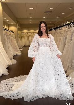 a woman is standing in front of some wedding dresses