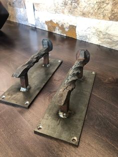 two pieces of metal sitting on top of a wooden floor next to eachother