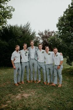 a group of men standing next to each other on top of a lush green field