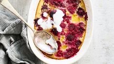 berry cobbler in a white dish with a spoon on the side next to it