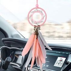 a car dashboard with a pink dream catcher hanging from it's center console