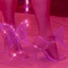 a woman's feet with purple glitter shoes and butterfly decorations on the toes, in front of a pink background