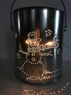 a metal pail with some lights on top of it and a light up figure in the middle